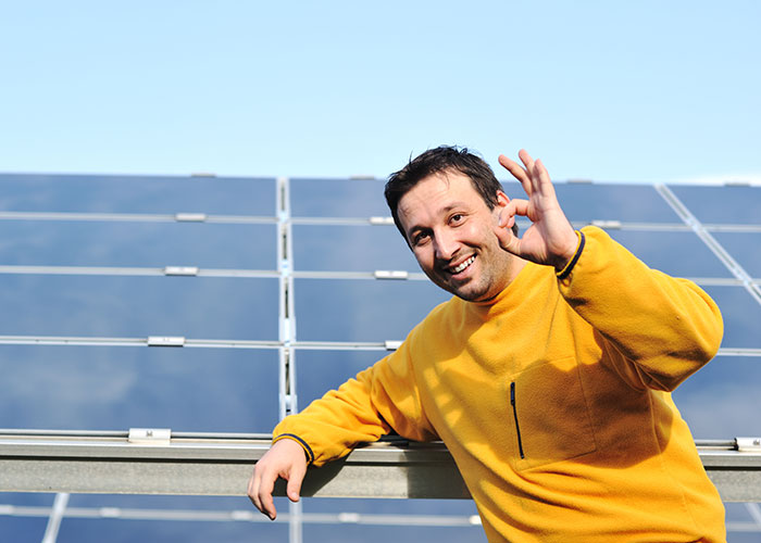 monteur zonnepanelen gebaart 'goed' met handgebaar op dak met zonnepanelen