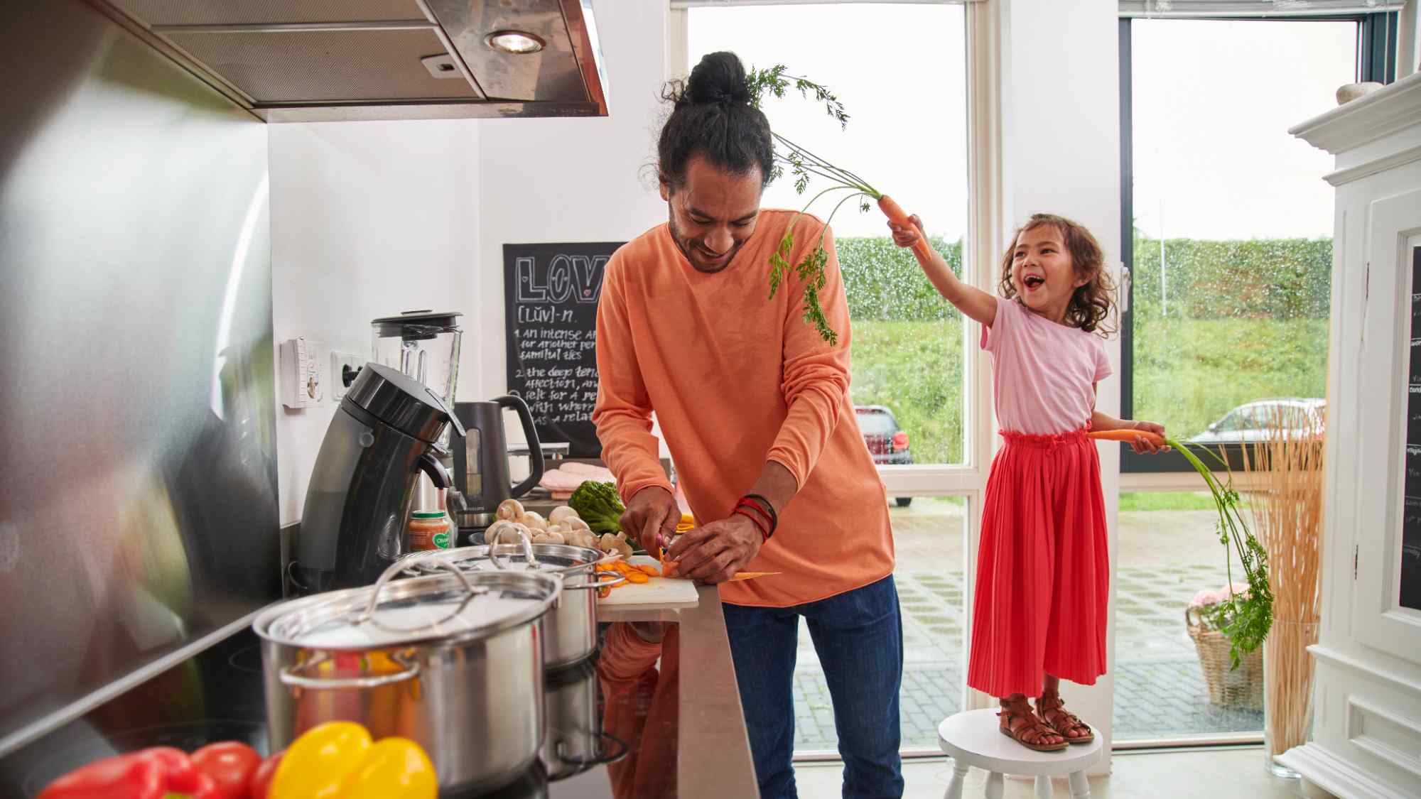 Man en kind spelen in de keuken