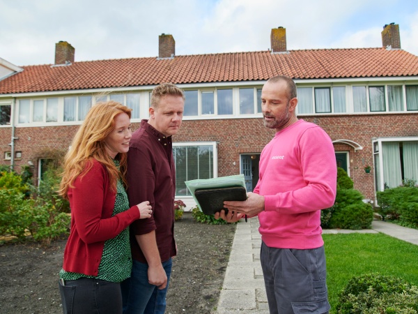 Adviseur staat buiten voor de huis, hij laat iets zien aan de man en vrouw.