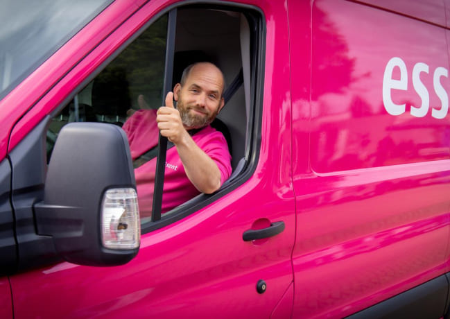 Lachende chauffeur in roze bus van Essent