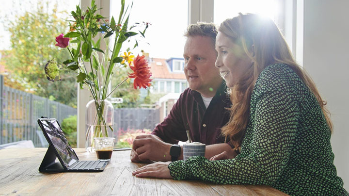 Man en vrouw lachen zittend naast een duurzame tafel.
