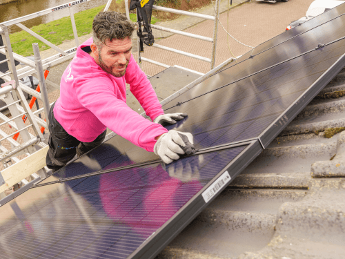 Monteur meet de zonnepanelen af op het dak.