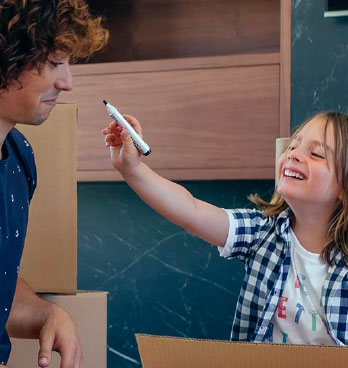 Kind schrijft tijdens verhuizing met stift op gezicht man.