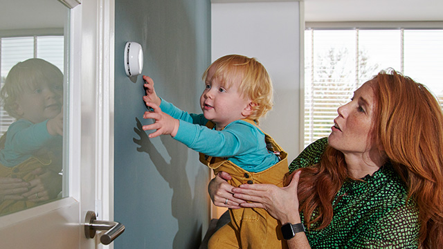 Vrouw en jongetje kijken naar lichtknop op de muur