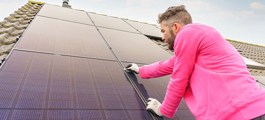 Monteur van Essent installeert zonnepanelen.