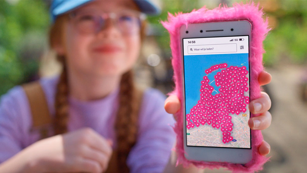 Een meisje houdt een telefoon vast met de Essent Laadpas app