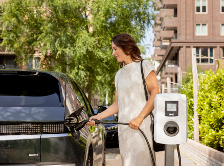 Vrouw laadt elektrische auto op met laadpaal.