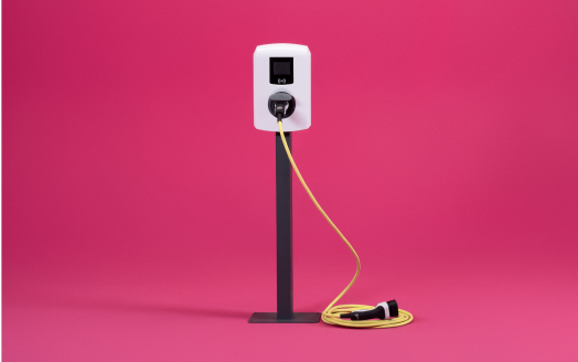 Laadpaal tegen een roze achtergrond aan.