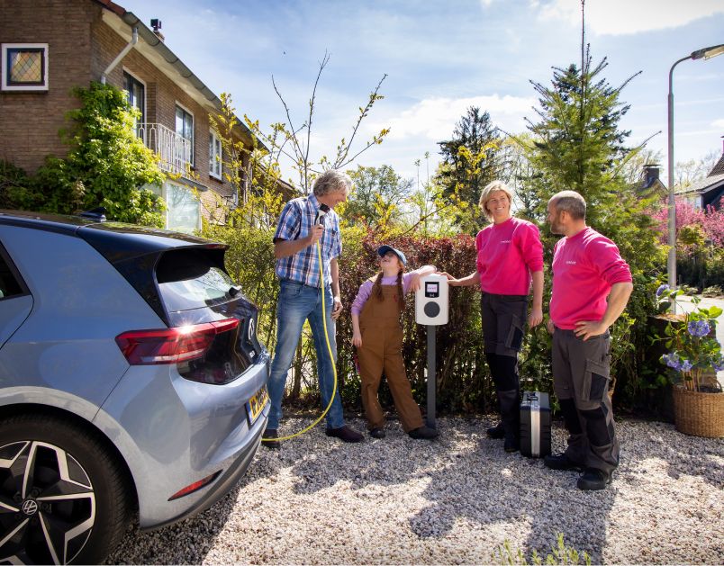 Twee monteurs van Essent staan met twee klanten bij een laadpaal