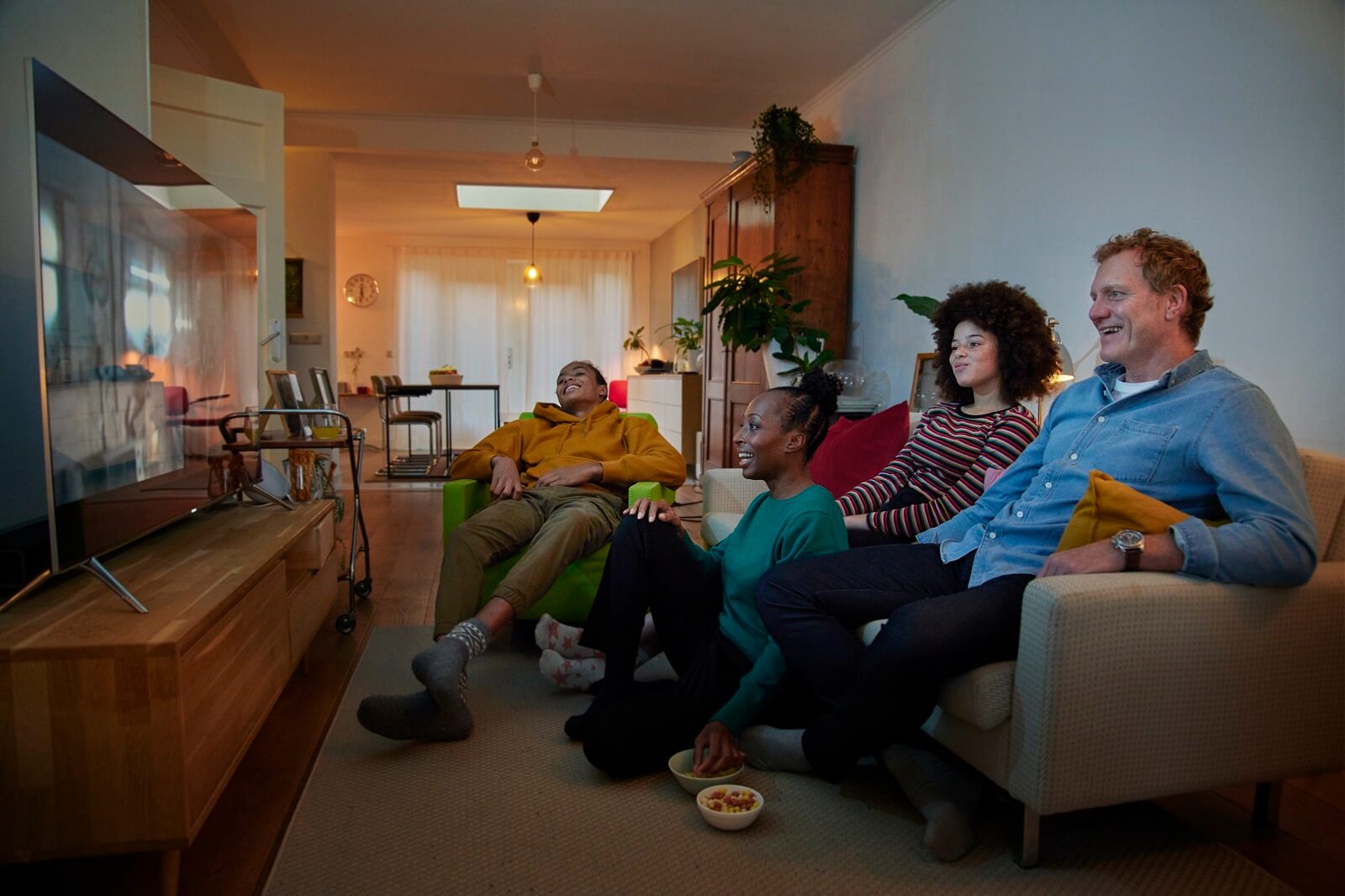 Gezin zit op de bank in woonkamer met spouwmuurisolatie.