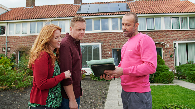 Adviseur van Essent laat man en vrouw kosten van isolatie zien op een iPad.