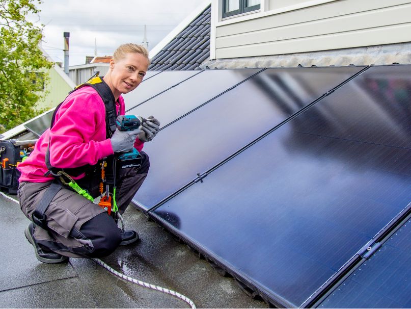 Een monteur van Essent  is bezig met de installatie van zonnepanelen