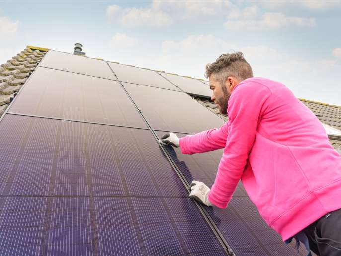Monteur plaatst zonnepanelen op dak