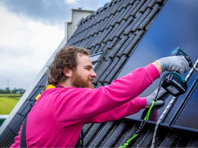 Monteur van Essent monteert zonnepanelen op een dak.