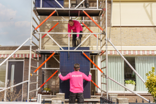 Servicemonteurs heisen zonnepaneel omhoog op steiger
