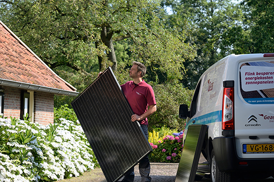 Man staat buiten met een zonnepaneel in zijn hand.