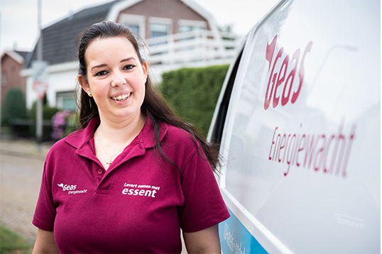 Vrouw kijkt lachend naast de Geas Energiewacht auto.