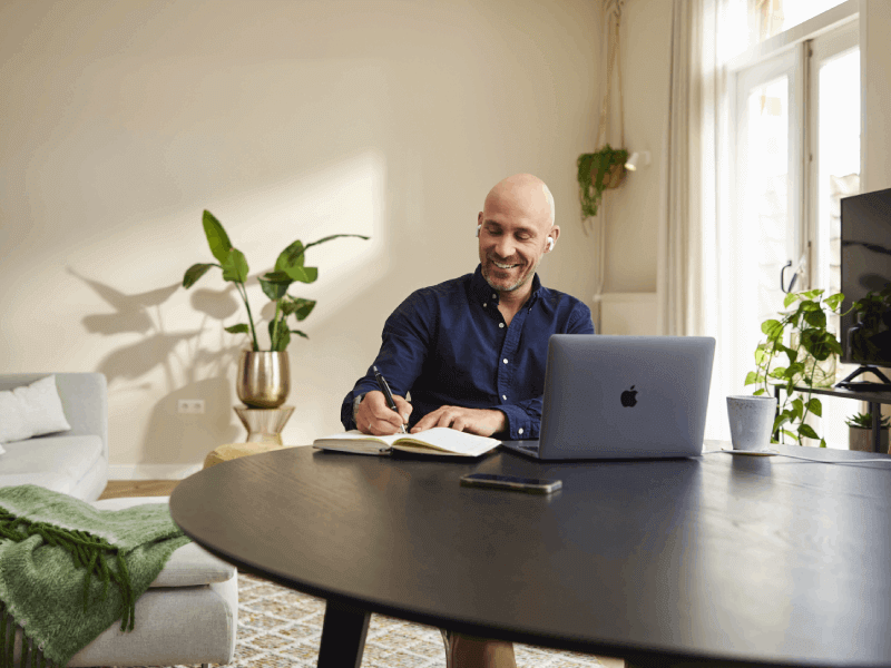 man zit achter laptop met oortjes in