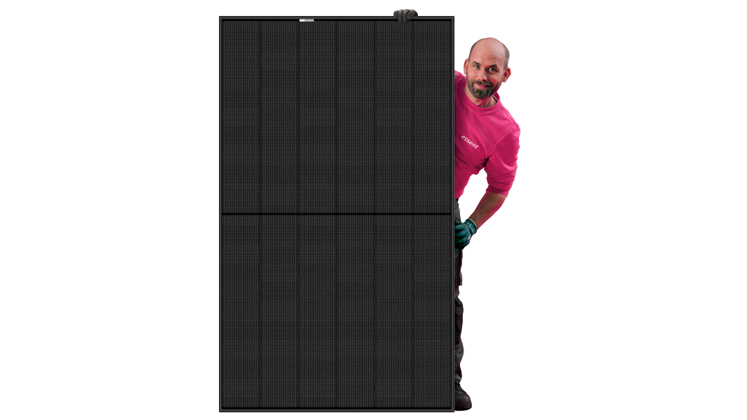 Freek van Essent staat achter een zonnepaneel en kijkt erachter vandaan in de camera. 